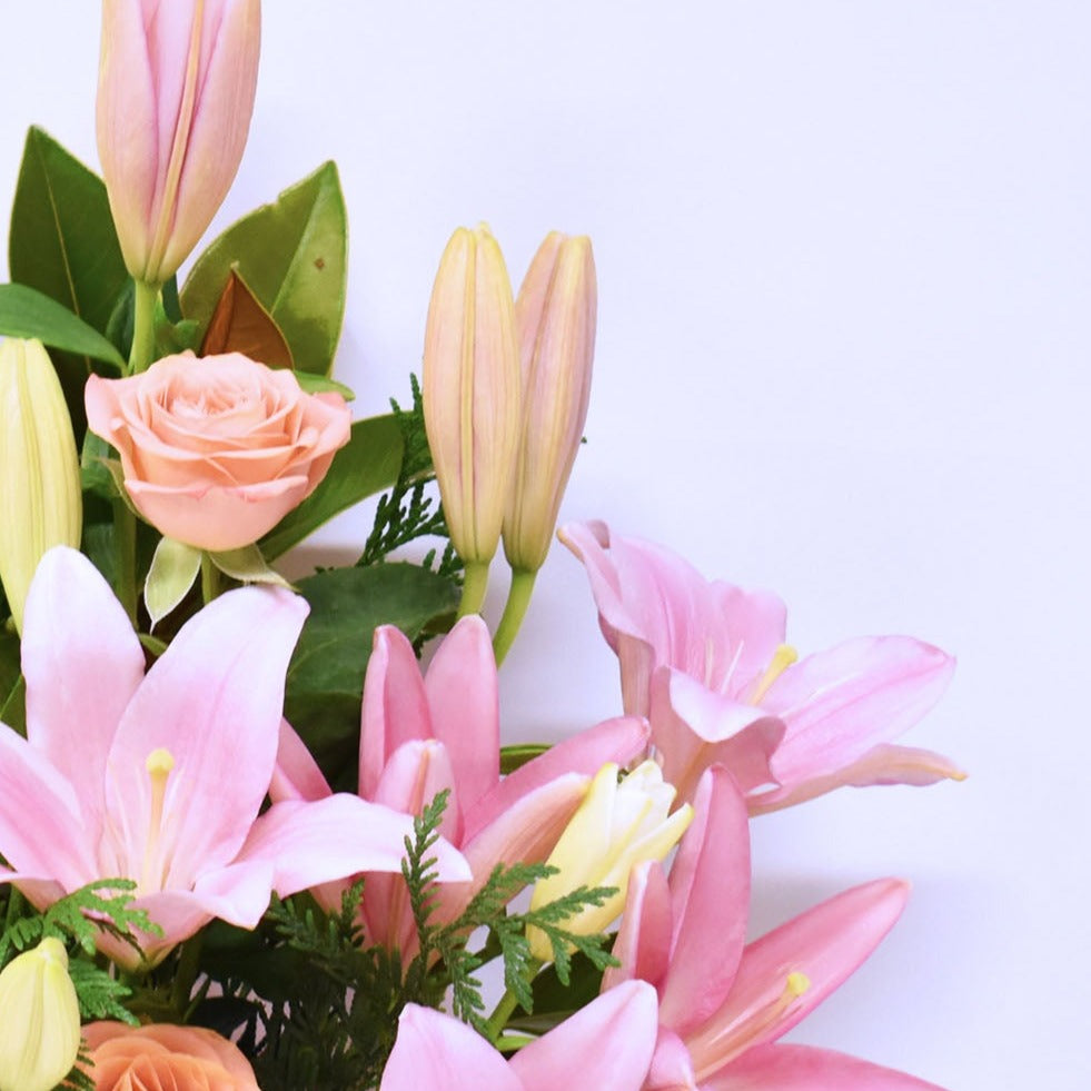 close up of pink roses and pink lilies in a flower box