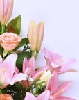 close up of pink roses and pink lilies in a flower box