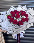 Bouquet of red roses in a decorative white wrap against a striped background